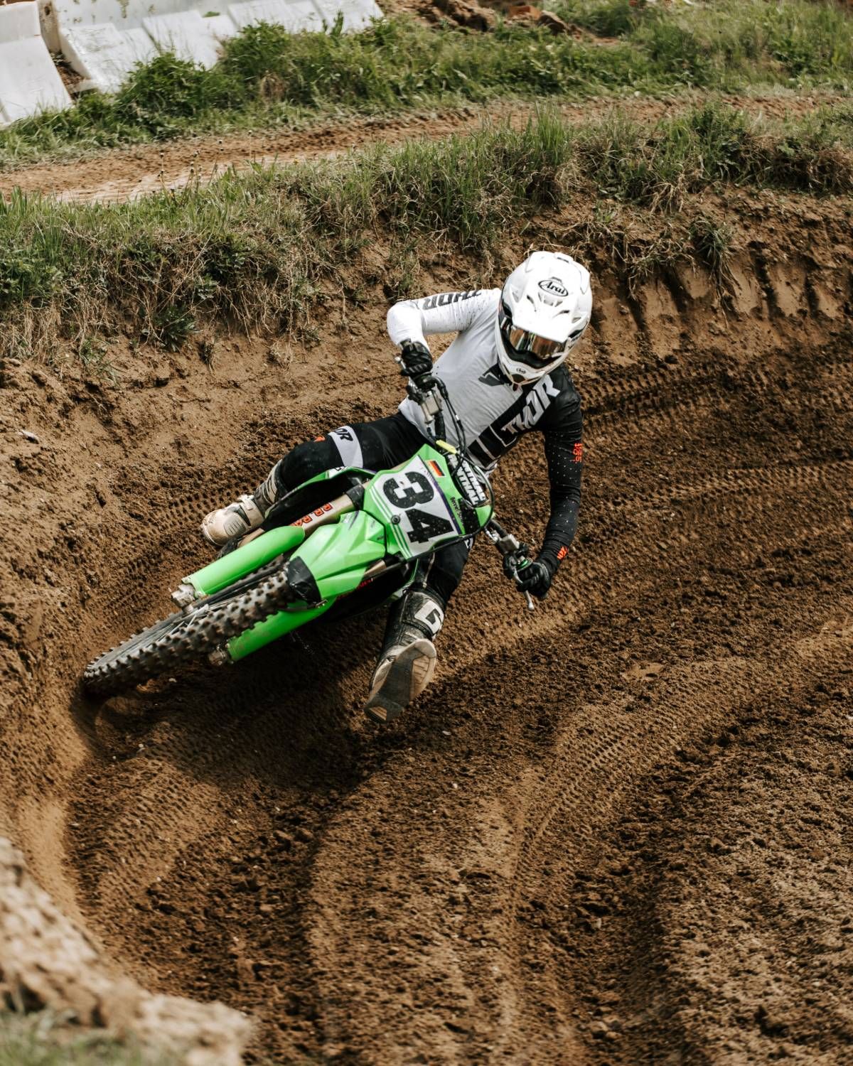 Motocross rider leaning a Kawasaki into a deep rut, rear tire loaded on the knob edges